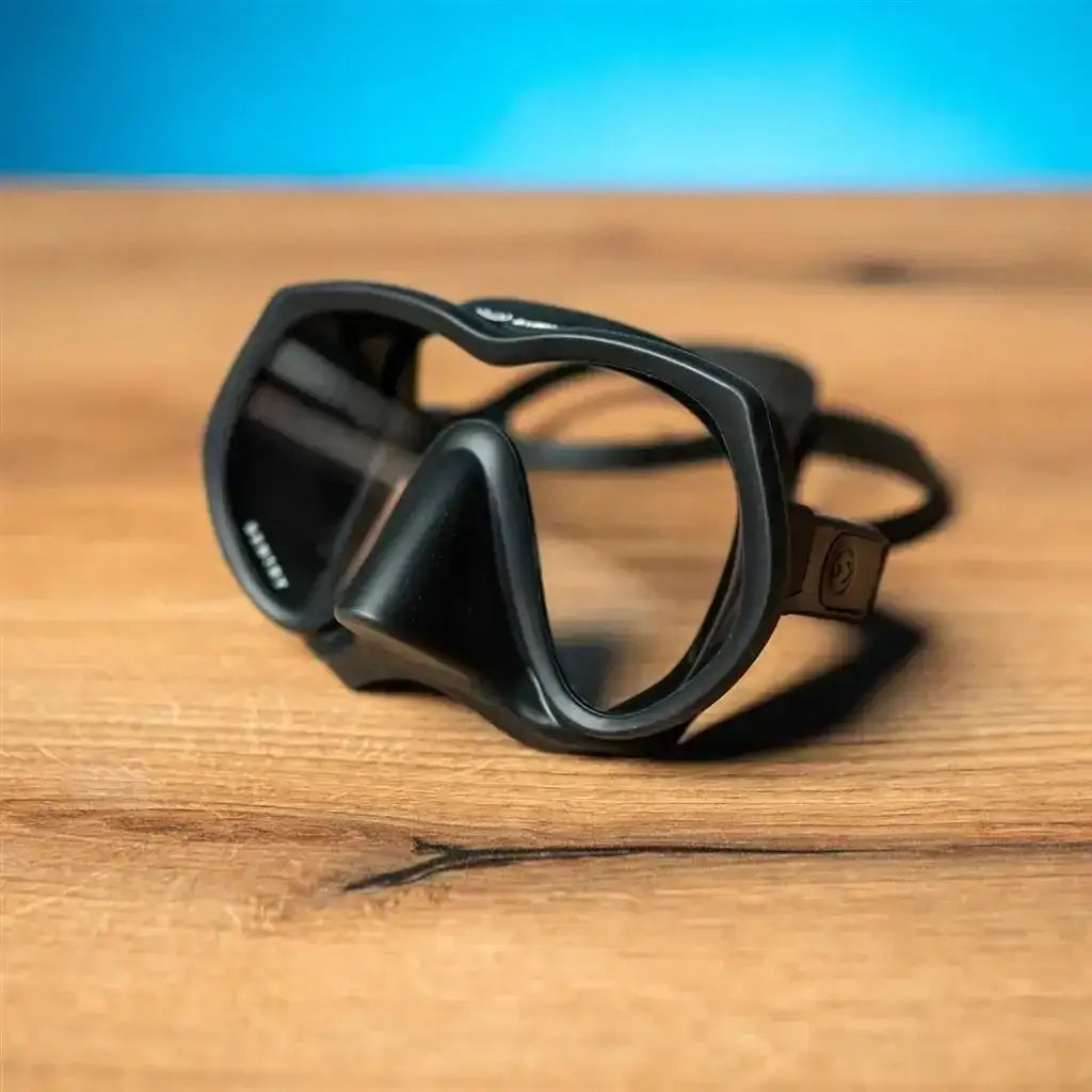Schwarze Taucher- oder Freediving-Maske aus Silikon auf Holztisch, Nahaufnahme, klarer Hintergrund