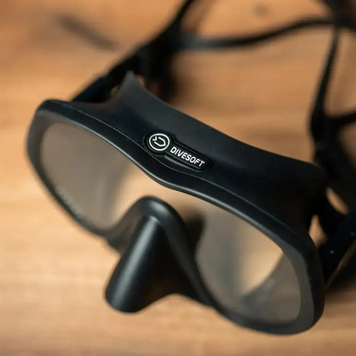 Schwarze Divesoft Tauchmaske mit klarem Glas auf Holzhintergrund, detailreiche Nahaufnahme