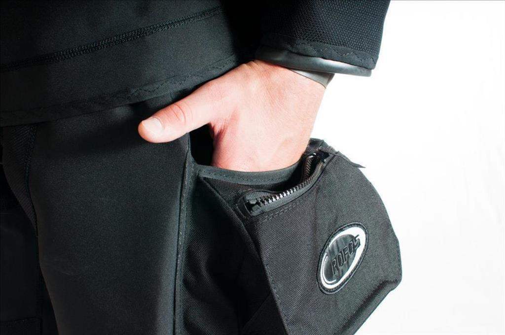 Hand steckt in der Tasche eines schwarzen Trockentauchanzugs mit Reißverschluss, Detailansicht.